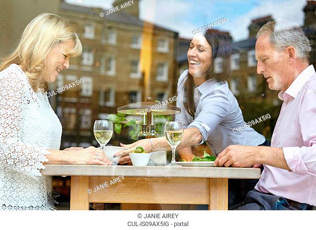 Waitress serving lunch to mature dating couple at restaurant table, London, UK