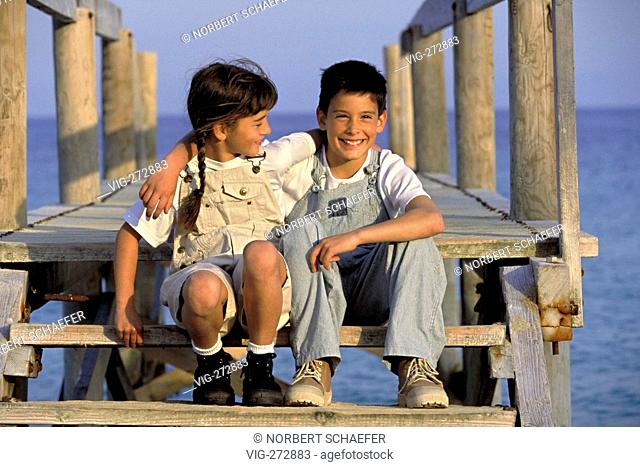 beach-scene, boy and girl sit together on a wooden landing stage at the sea  - DEUTSCHLDEU, 25/06/2006