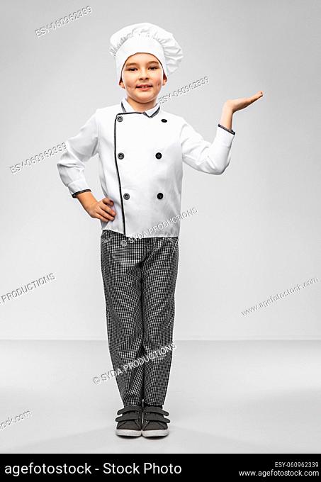smiling boy in chef's toque holding something