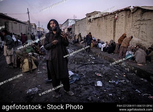 14 November 2022, Afghanistan, Kabul: Afghan men consume drugs on a side street of a market as dusk sets in. Drug addiction has been a long standing problem in...