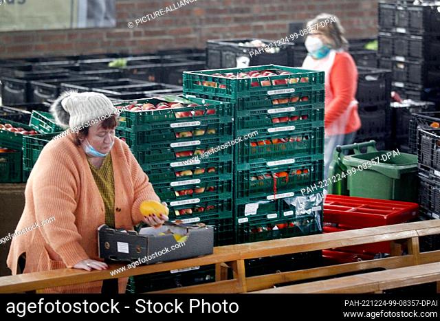 13 December 2022, North Rhine-Westphalia, Oberhausen: Employees of the Oberhausen food bank sort fruit and vegetables for their customers in the nave of a...
