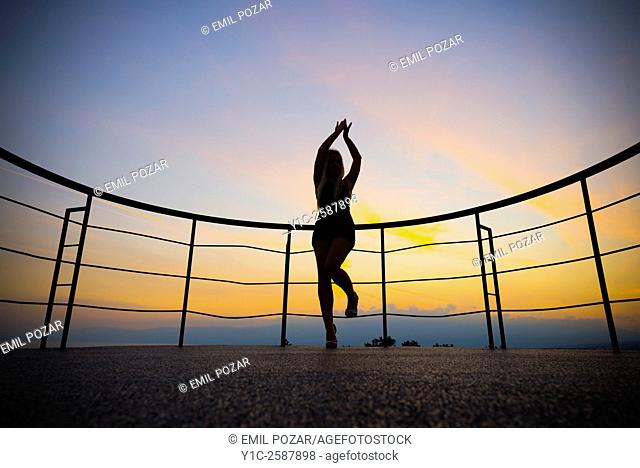 Happy young woman silhouetting against sunset sky