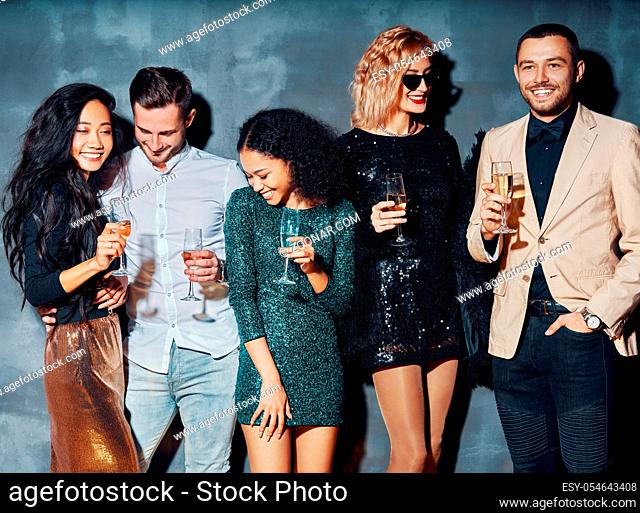 Diverse group of people enjoy party and have fun. Young friends drinking champagne and hanging out at night club