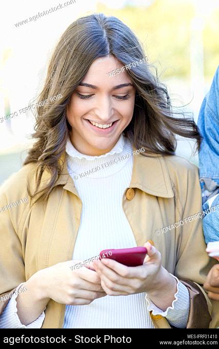 Smiling woman using smart phone on university campus