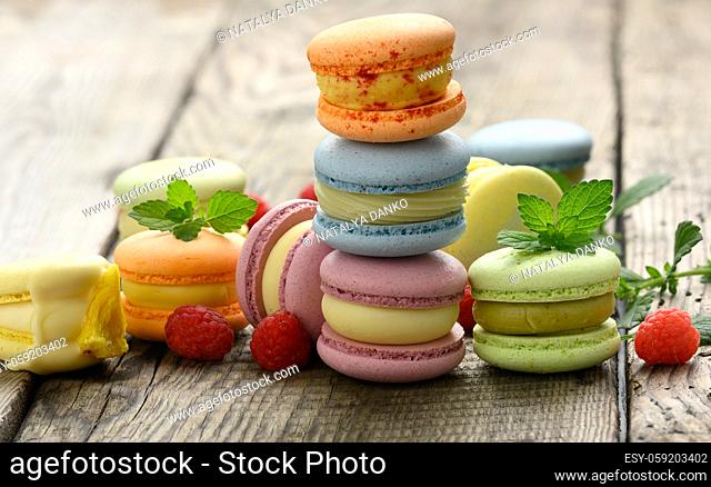 stack of baked multicolored macarons and different flavors on a gray wooden table, delicious dessert, close up