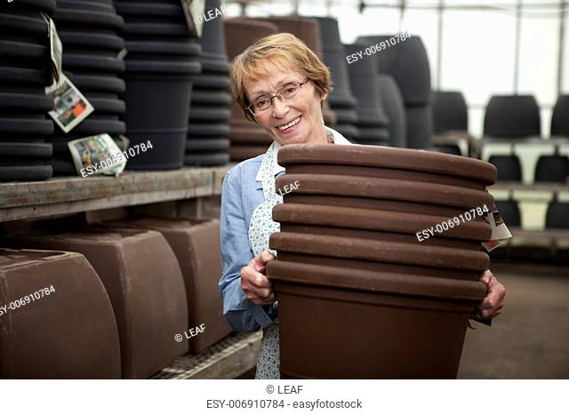 Portrait of a senior worker in garden center with large plant pots