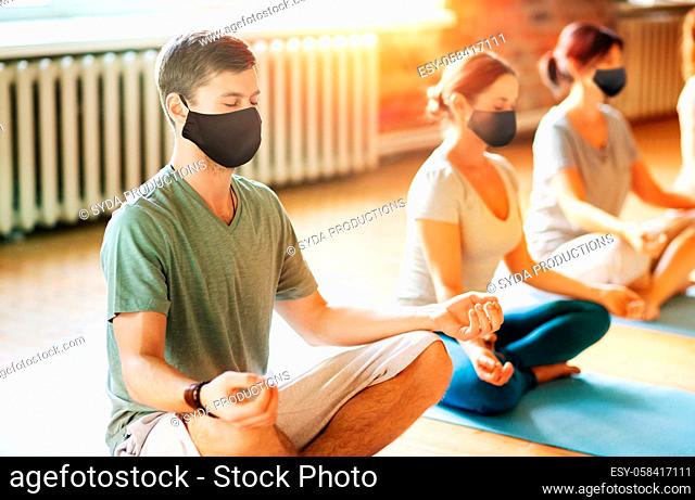 group of people in masks doing yoga at studio