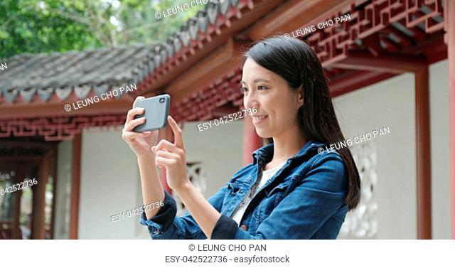 Woman taking photo on cellphone in Chinese garden
