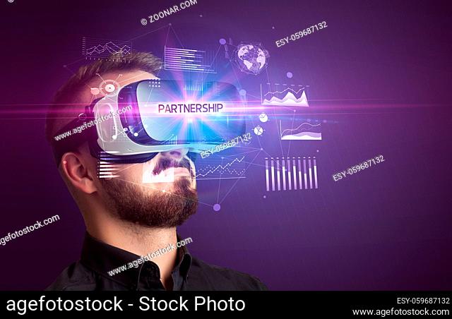 Businessman looking through Virtual Reality glasses with PARTNERSHIP inscription, new business concept