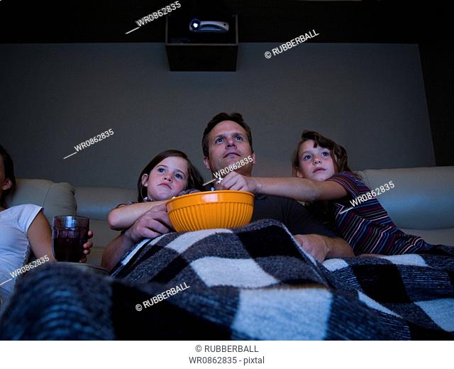 Father and daughters watching movie in home theater