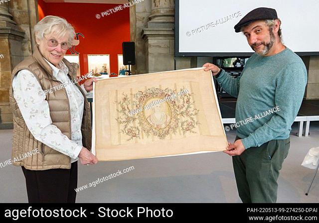 13 May 2022, Lower Saxony, Hanover: Gabriele Berliner (l) and Joe Fendel show an embroidery work in an exhibition room at the Museum August Kestner