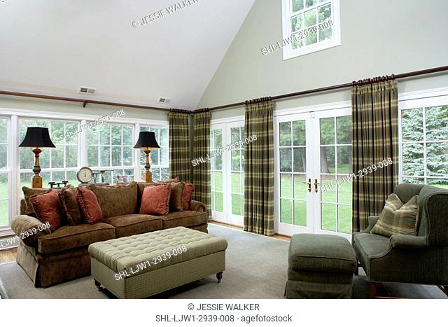 FAMILY ROOMS: Traditional high ceilings, french doors and long windows, continuous cutain rod, plaid curtains, earth tones, dark brown sofa, tufted ottoman