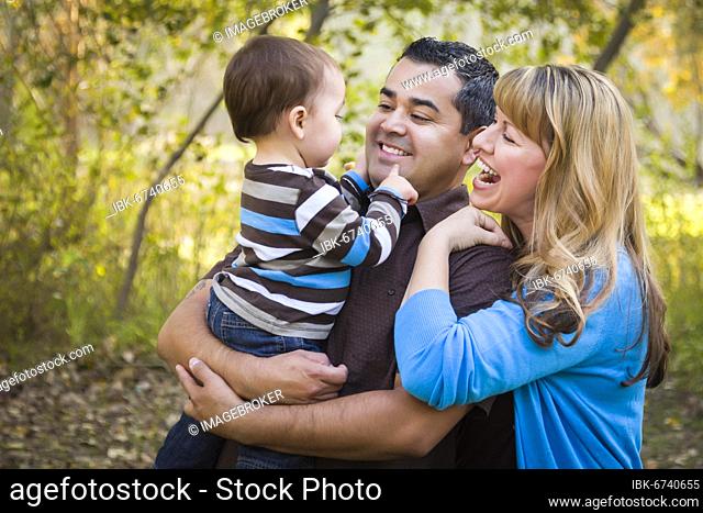 Happy mixed-race ethnic family having fun playing in the park