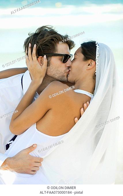 Bride and groom kissing at the beach