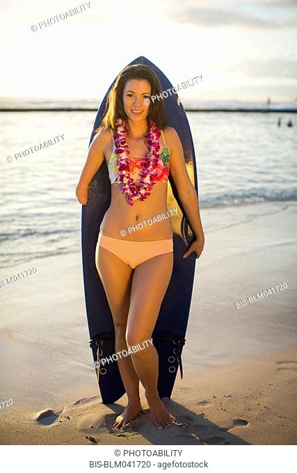 Mixed race amputee holding surfboard on beach