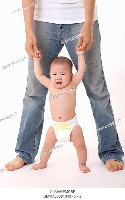 Father helping crying baby girl stand