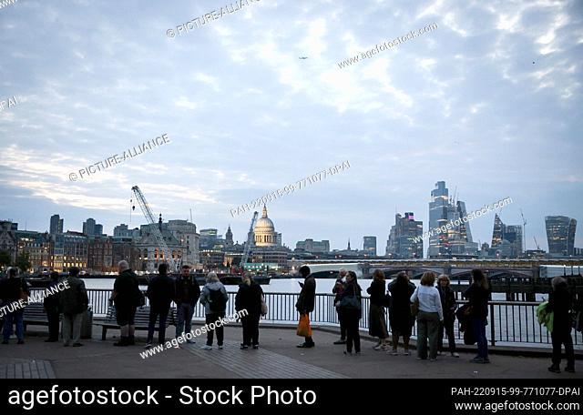 15 September 2022, Great Britain, London: Numerous people stand in a long queue on the Thames between Millennium Bridge and Parliament to say goodbye to the...