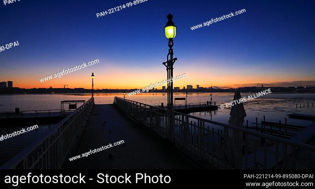 14 December 2022, Hamburg: The sky lights up before sunrise at the Rabenstraße pier on the Alster. Photo: Christian Charisius/dpa