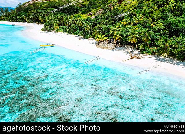 Aerial view of boat moored at uninhabitable island with tropical beautiful azure blue lagoon. Seychelles