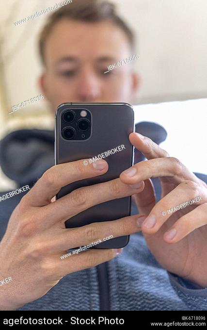 Junger Mann tippt auf, hält iPhone 11 Pro, Smartphone