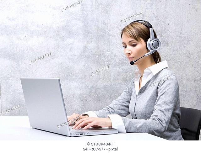 Woman in office with headset using laptop