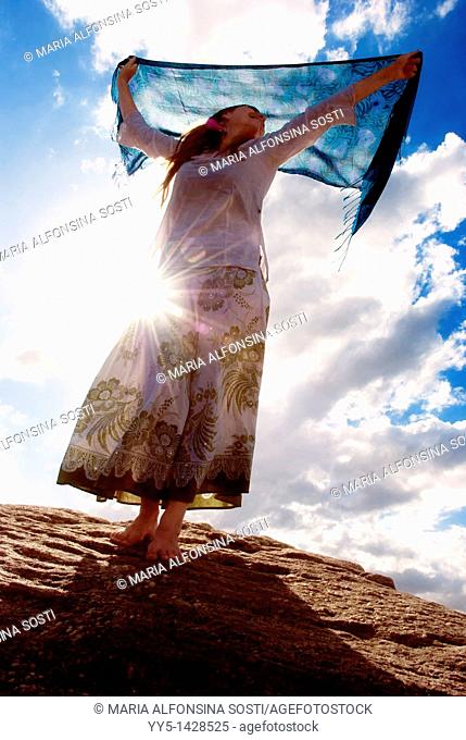 Young woman, from light, holding a handkerchief in his hand, standing on the rock