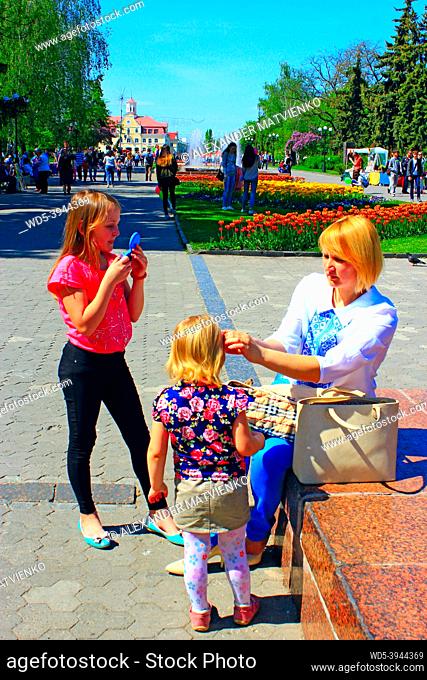 mother corrects her daughter's hair during a walk through the spring town. Family walk through the spring town