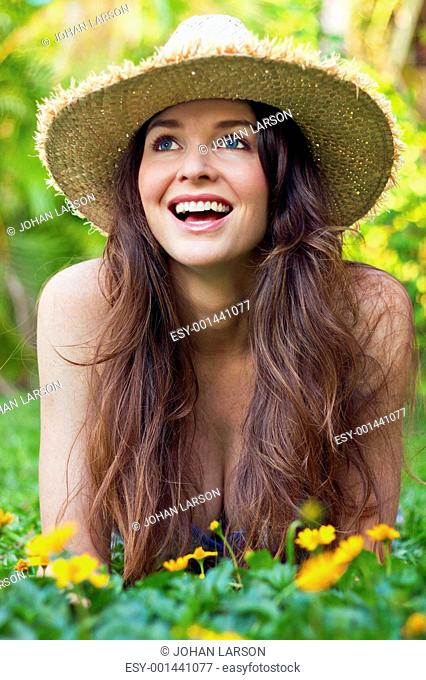 Beautiful young woman lying in meadow laughing
