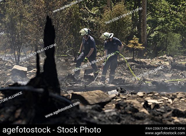 13 June 2023, Hesse, Oberursel: Firefighters extinguish nests of embers and flames flaring up again in a forest fire on the Altkönig in the Taunus