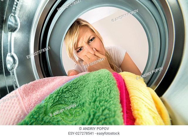Close-up Of Young Woman Inserting Stinky Clothes In Washing Machine