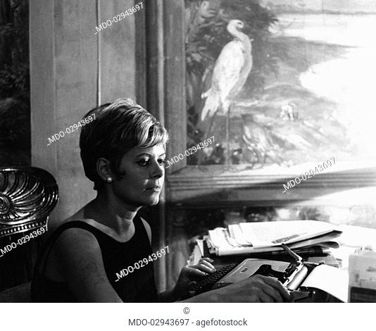 Italian actress and journalist Lianella Carell sitting at the typewriter. Rome, 1963