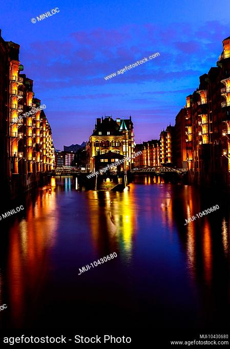 The Warehouse District - Speicherstadt in twilight. Tourism landmark of Hamburg. View of Wandrahmsfleet in light of lantern lamp