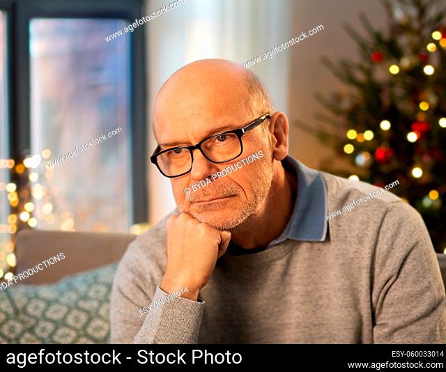 sad senior man in glasses at home on christmas