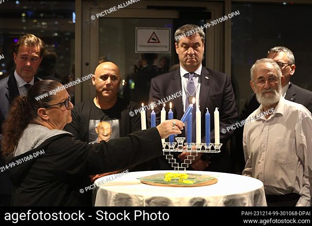 14 December 2023, Israel, Tel Aviv: Relatives of the hostages kidnapped by Hamas light Hanukkah candles in front of Markus Söder (CSU, center)