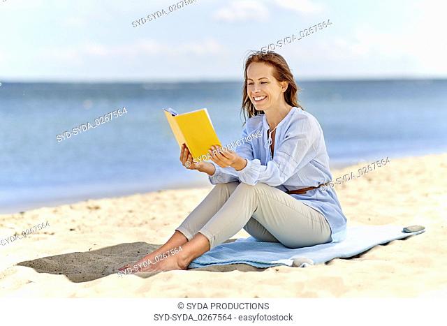 happy smiling woman reading book on summer beach