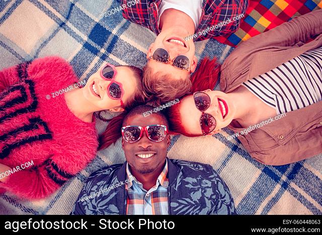 Closeup picture of best friends making selfies on picnic. People in sunglasses lying on picnic rug and smiling for camera