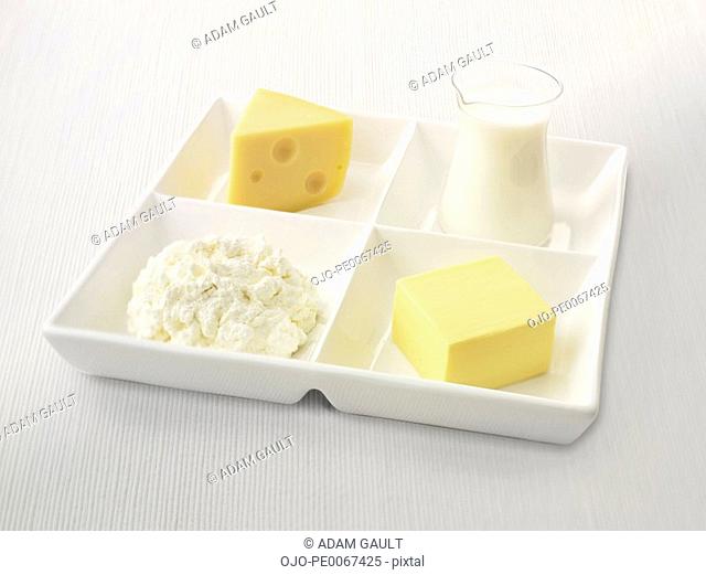 Close up of sectioned plate with cheese, cottage cheese, butter and milk