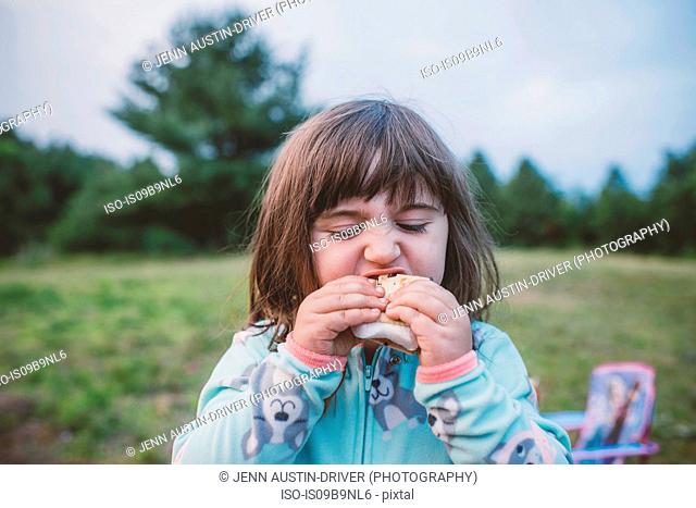 Young girl, outdoors, eating s'more, close-up