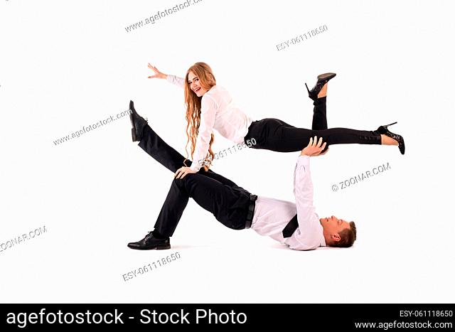 Side view of male manager in formal wear lifting cheerful female colleague against white background
