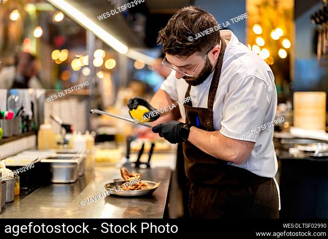 Chef wearing glove grating lemon on food in plate