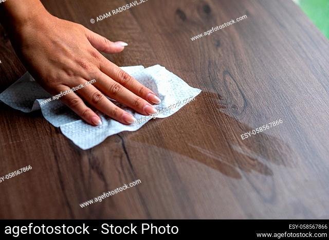 Woman's hand cleaning home office table surface with wet wipes