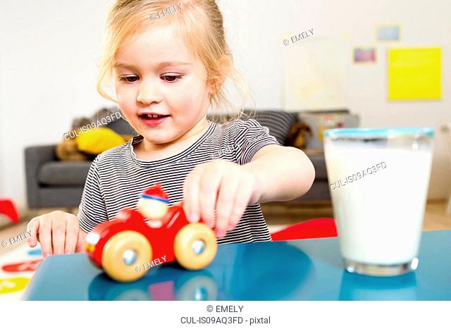 Girl playing with toy car at home