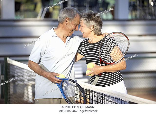Tennis court, senior-pair, net, gaze-contact, embrace, laughs, detail, series, people, seniors, pair, 60-70 years, tennis, tennis-players, sport, tennis-games