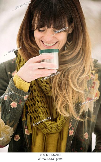 A woman in snow in winter, having a warm drink