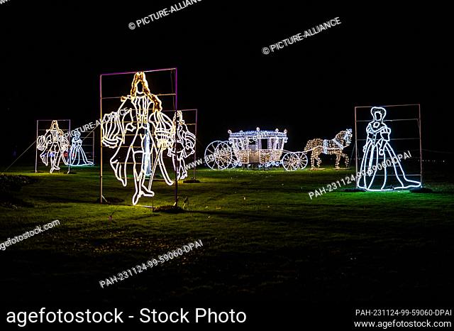 SYMBOL - 22 November 2023, Baden-Württemberg, Mainau: A wire mesh in the shape of a carriage and aristocrats glows in the dark at the Christmas Garden on the...
