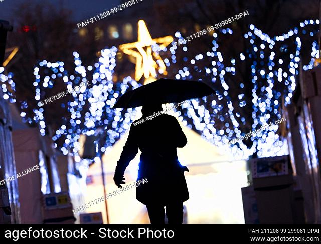 08 December 2021, Hamburg: A passerby walks through a closed Christmas market downtown early this morning in a light snowfall