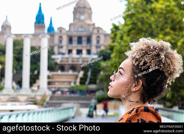 Beautiful woman with tattoo on neck looking away while standing in city