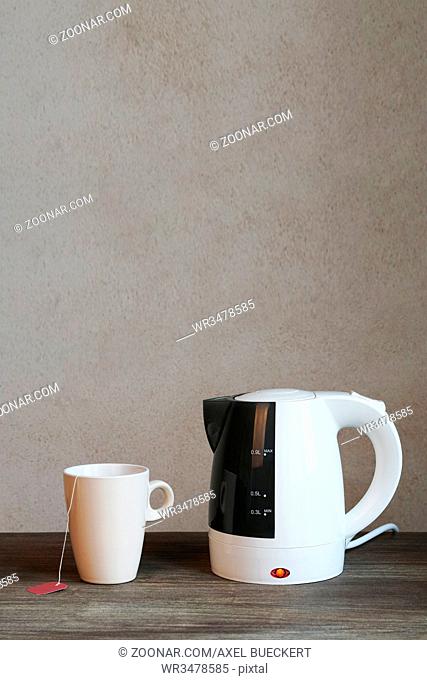 tea making facilities with electric water kettle teacup and teabag, vertical background with copy space