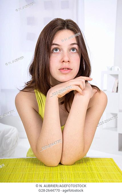 Teenage girl resting her chin on her hands and daydreaming