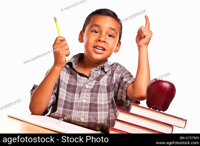 Adorable hispanic boy raising his hand sitting with books, apple, pencil and paper isolated on a white background